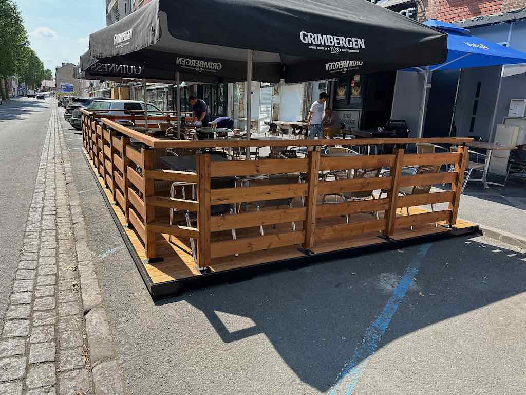 Terrasse en bois de la Brasserie de la Place avec des parasols Grimbergen et Guinness