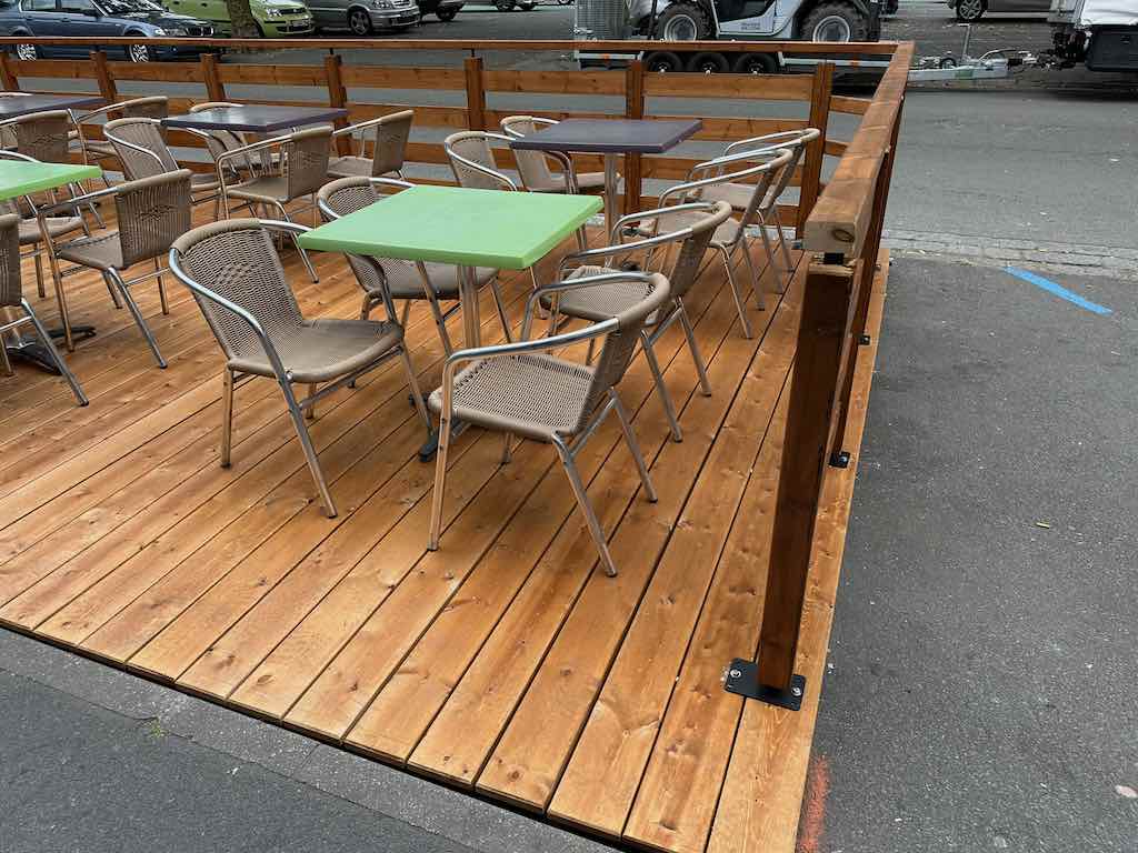 Tables et chaises en osier et métal sur une terrasse en bois à la Brasserie de la Place