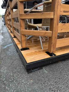 Terrasse saisonnière urbaine installée sur plots, avec une structure en bois et des bordures métalliques